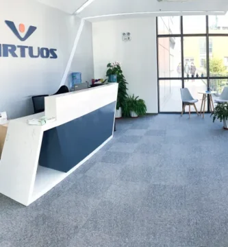 Virtuos logo with a background of gaming consoles.