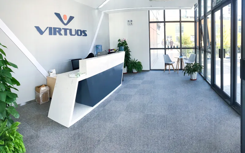 Virtuos logo with a background of gaming consoles.