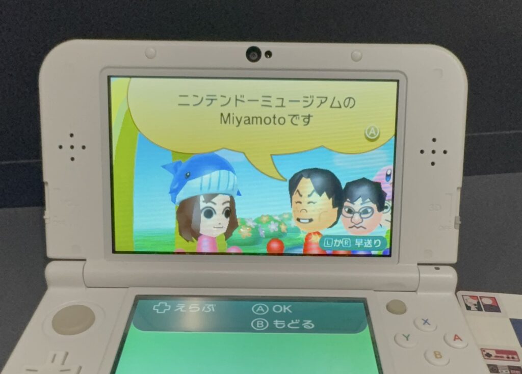 Visitors holding 3DS consoles at the Nintendo Museum in Kyoto, excited about StreetPass Miis featuring Shigeru Miyamoto