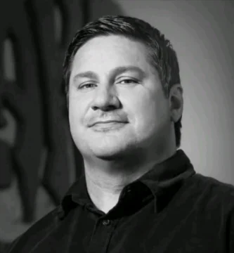 Portrait of Bill Petras, Blizzard art director, with Overwatch and World of Warcraft artwork in the background