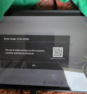 Nintendo Switch 2 console with red warning sign overlay indicating ban risk from secondhand purchases